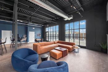 A modern office space with blue chairs and orange couches.